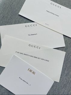 three white envelopes with gucci written on them sitting on a gray cloth covered table