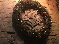 a wreath on the side of a brick wall with a coat of arms surrounded by greenery