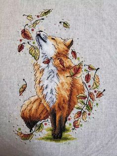 a cross stitched picture of a fox with autumn leaves on it's back