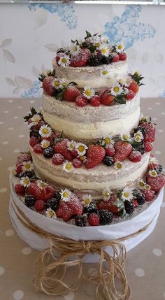 a three tiered cake with strawberries and daisies