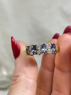 a woman's hand holding an old diamond and sapphire ring with three stones on it