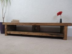 a wooden shelf sitting on top of a carpeted floor next to a potted plant