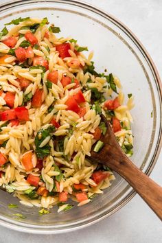 a bowl filled with pasta salad and a wooden spoon