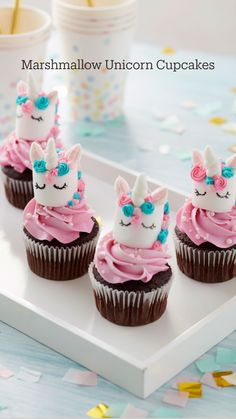 three cupcakes with pink frosting and unicorn decorations