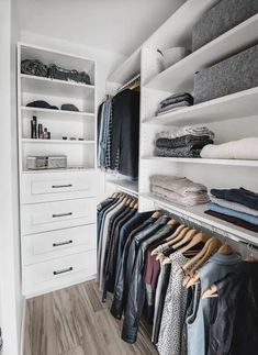 an organized closet with white shelving and lots of clothes