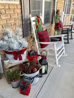 three white rocking chairs decorated with christmas decorations and pine cones on the front porch for holiday