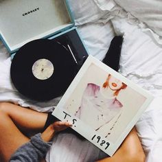 a woman laying on top of a bed next to a record player and an album