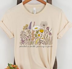 Quality: Our Women's Christian graphic t-shirts are professionally designed and printed with aesthetic love in the USA. We use the highest quality inks on Premium Bella + Canvas shirts for a look you can be proud of. You'll love the soft feel, comfort, and unique look of this Wildflower t-shirt. Imagine the compliments you'll receive. Perfect if you're looking for a Wildflower shirt, cottagecore clothing, Floral Shirt, Nature Shirt, or Christian clothing. Fit: Fits true to size for comfort that Wildflower Shirt Design, Plant T Shirt Designs, Pretty T Shirts, Cottagecore Graphic Design, T Shirt Phrases, T-shirt Designs, Flower Tshirt Design, Sweatshirt Painting, Wildflower Shirts