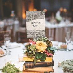 a stack of books sitting on top of a table covered in flowers and greenery