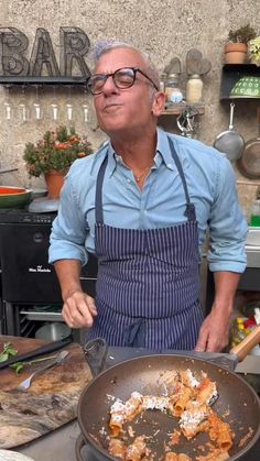 a man standing in front of a frying pan filled with food