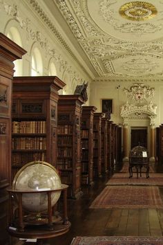 an old library with many bookshelves and a globe on the floor in front of it