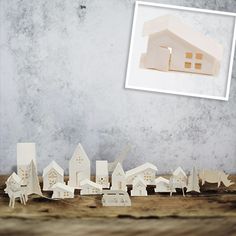 a group of small wooden houses sitting on top of a table next to a wall