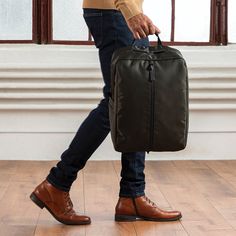 a man is carrying a large bag on the floor in front of a window,