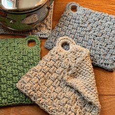 three crocheted placemats sitting on top of a wooden table next to a pot holder