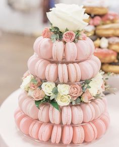 a three tiered cake made out of macaroons with flowers and leaves on top