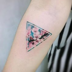 a small triangle tattoo with flowers on the inside of it, and an arrow in the middle