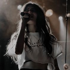 a woman with long hair holding a microphone in front of her face while standing on stage