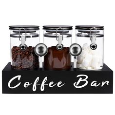 three glass jars filled with coffee beans and marshmallows on top of a black sign