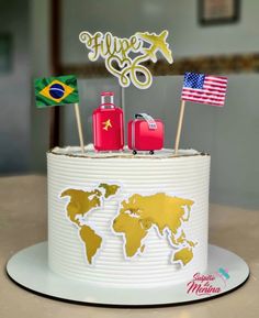 a cake decorated with flags and suitcases on top of a white plate, in the shape of a world map