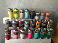 many different colored yeti cups are stacked on top of each other in front of a white wall