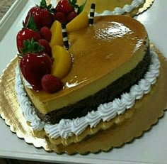 a heart - shaped cake with fruit on top is sitting on a tray in the kitchen