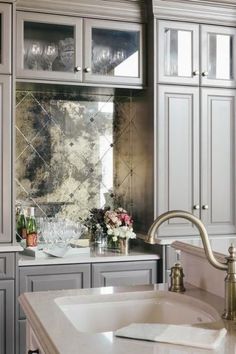 a kitchen filled with lots of gray cabinets and white counter top space next to a sink