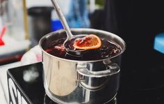 a silver pot filled with liquid and an orange slice