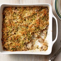 a casserole dish with meat and vegetables in it on a wooden table next to plates