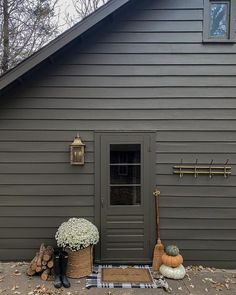 the front door of a gray house with fall decorations