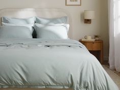 a bed with blue sheets and pillows in a bedroom