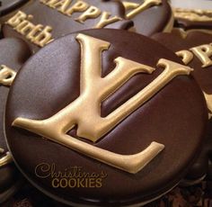 chocolate cookies decorated with the letter l and gold icing are on top of each other