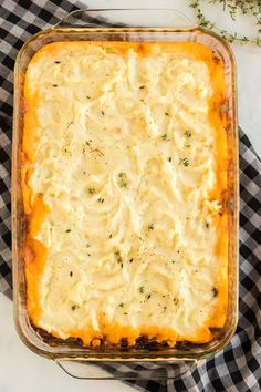 a casserole dish with cheese and herbs in it on a checkered cloth