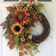 a wreath with sunflowers, leaves and berries is hanging on the front door