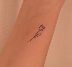 a small tattoo on the wrist of a woman with a single tulip in it