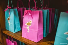 colorful shopping bags with flamingos on them are sitting on a shelf in a store