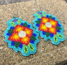 two pairs of beaded earrings sitting on top of a stone slab next to each other