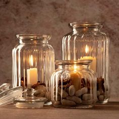 three glass jars filled with rocks and lit candles