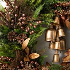 a christmas wreath with bells and pine cones on it, surrounded by evergreen leaves and other greenery