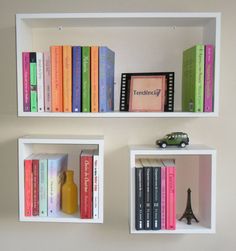 three white shelves with books and toy cars on them