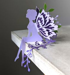 a paper cut fairy sitting on top of a table