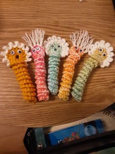 four crocheted toothbrush holders with eyes on them sitting on top of a wooden table