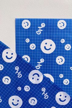 two pieces of blue paper with smiley faces on them