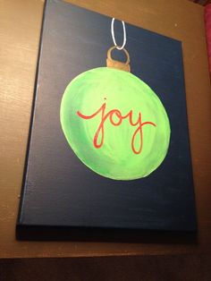 a green ornament with the word joy painted on it