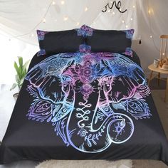 a bed with an elephant design on the comforter and pillow cases in purple, blue, and black