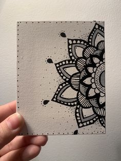 someone holding up a piece of paper with a black and white flower design on it