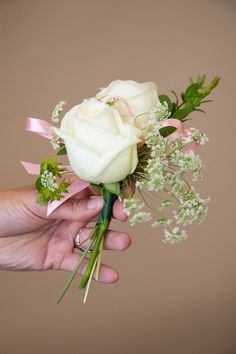 a person holding a white rose and baby's breath