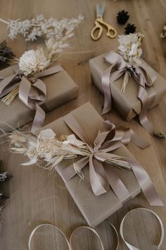 several wrapped presents with ribbons and bows on a wooden table next to scissors, flowers and other items