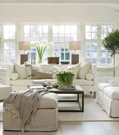 a living room filled with white furniture and windows