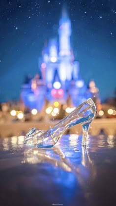 a glass shoe sitting on top of a table in front of a castle at night