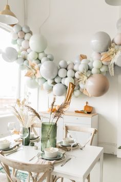 a dining room table set for two with balloons in the shape of flowers and leaves